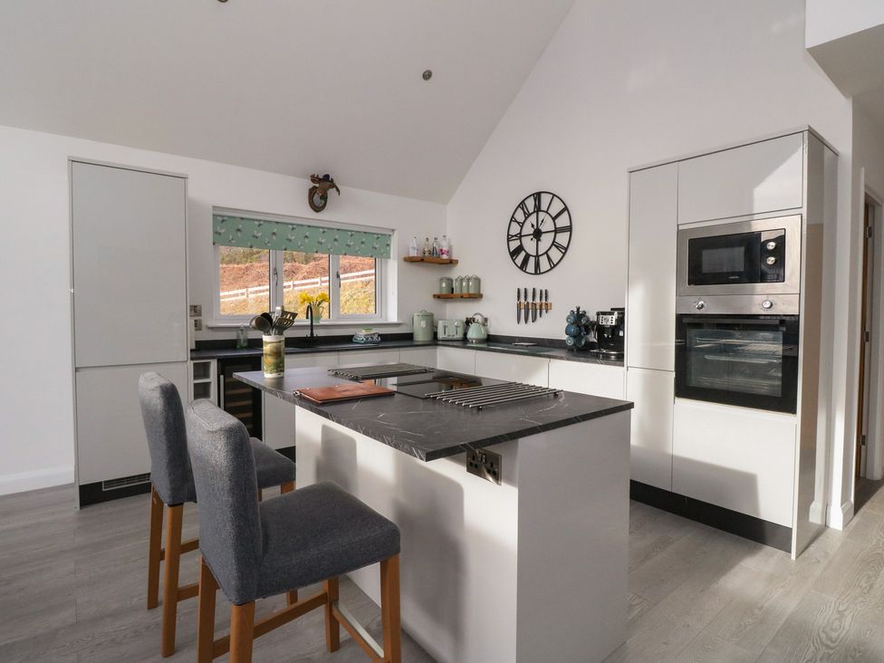 A kitchen with an island and bar stools at Eildan in Fort William
