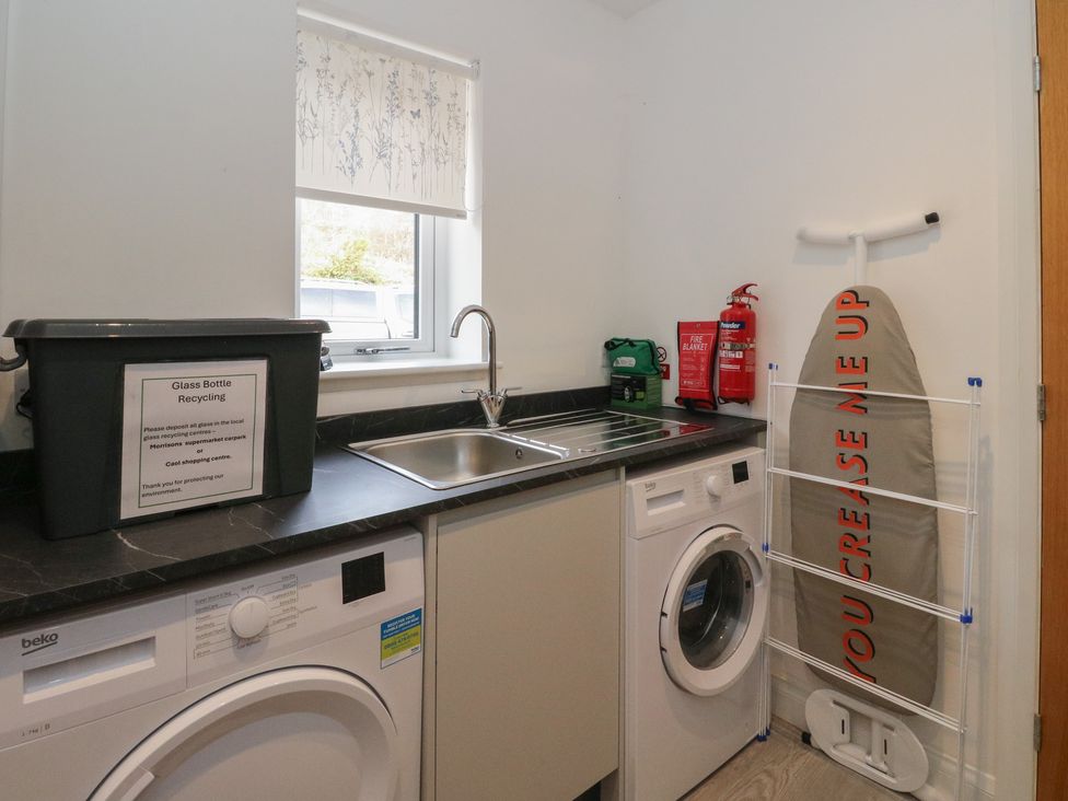 A laundry room with a washing machine and sink at Eildan in Fort William