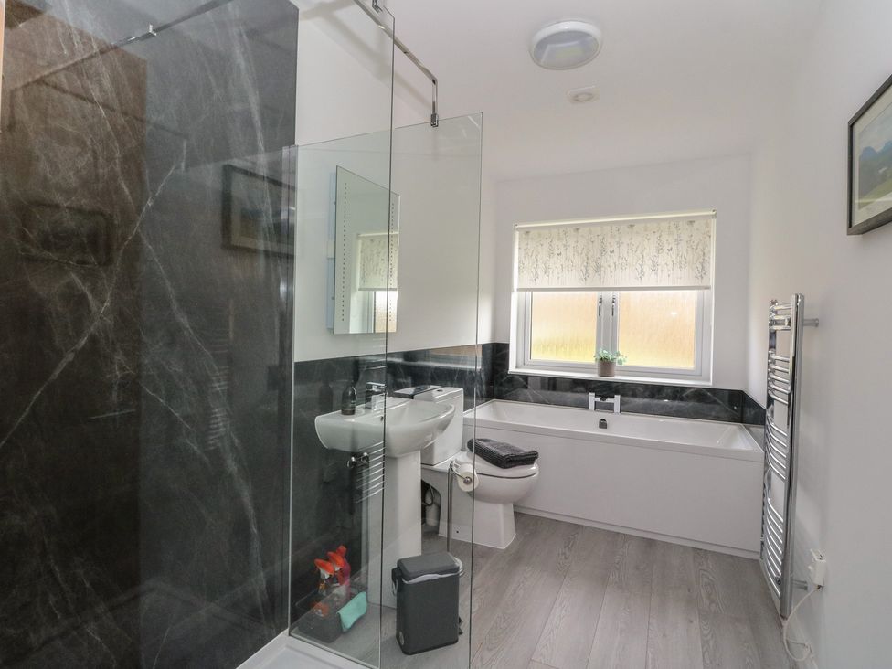 A bathroom with a shower, bathtub, sink and a window at Eildan in Fort William