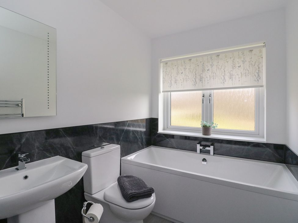A bathroom with a bathtub, toilet, sink, and window at Eildan in Fort William