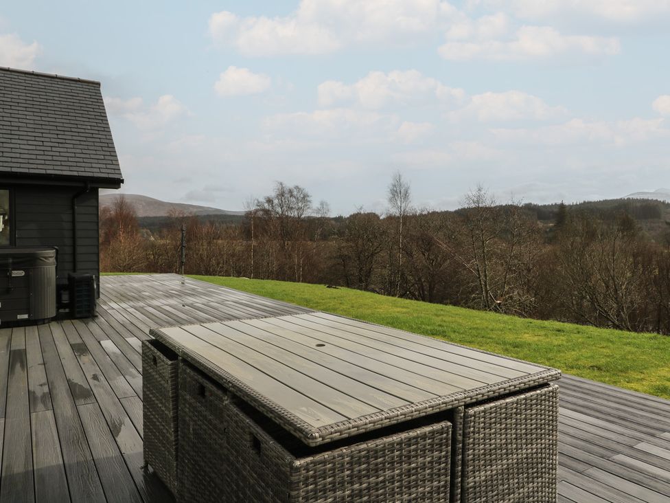 An outdoor deck with a furniture table and hottub at Eildan in Fort William