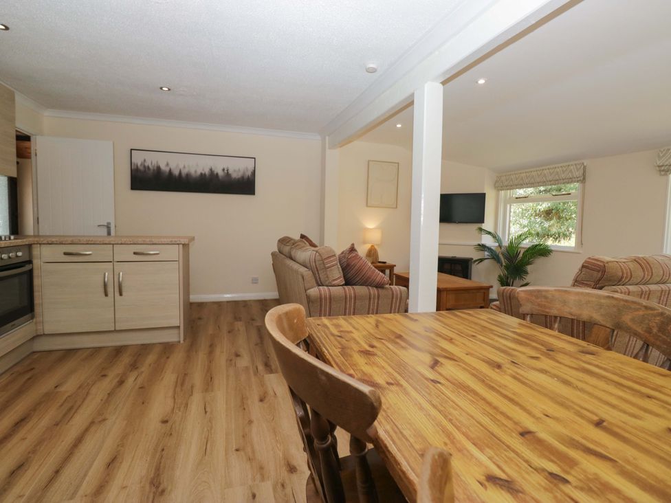 A living room with kitchen area and dining table at Beech Timber Lodge in Keswick