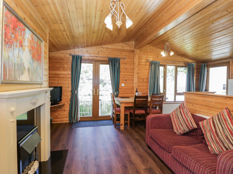A living room with a sofa and dining table at Elm Lodge in Keswick