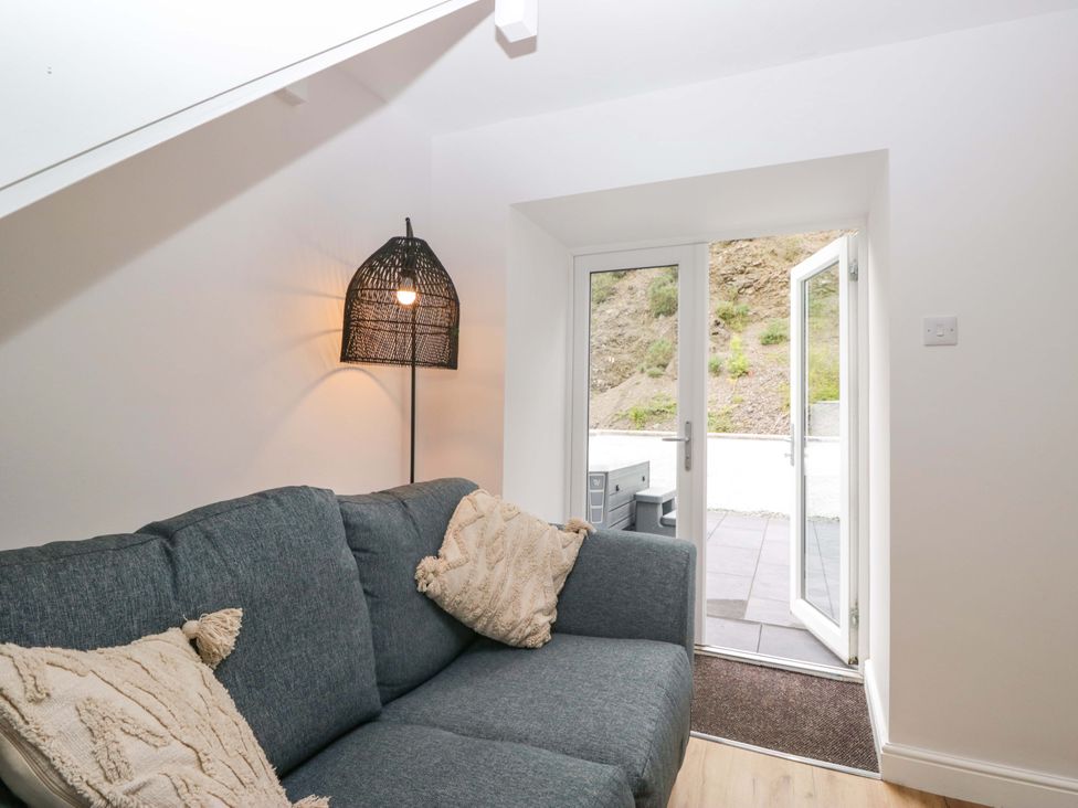 A living room with a sofa and a door leading outside at Riverside Cottage No 5 in Keswick