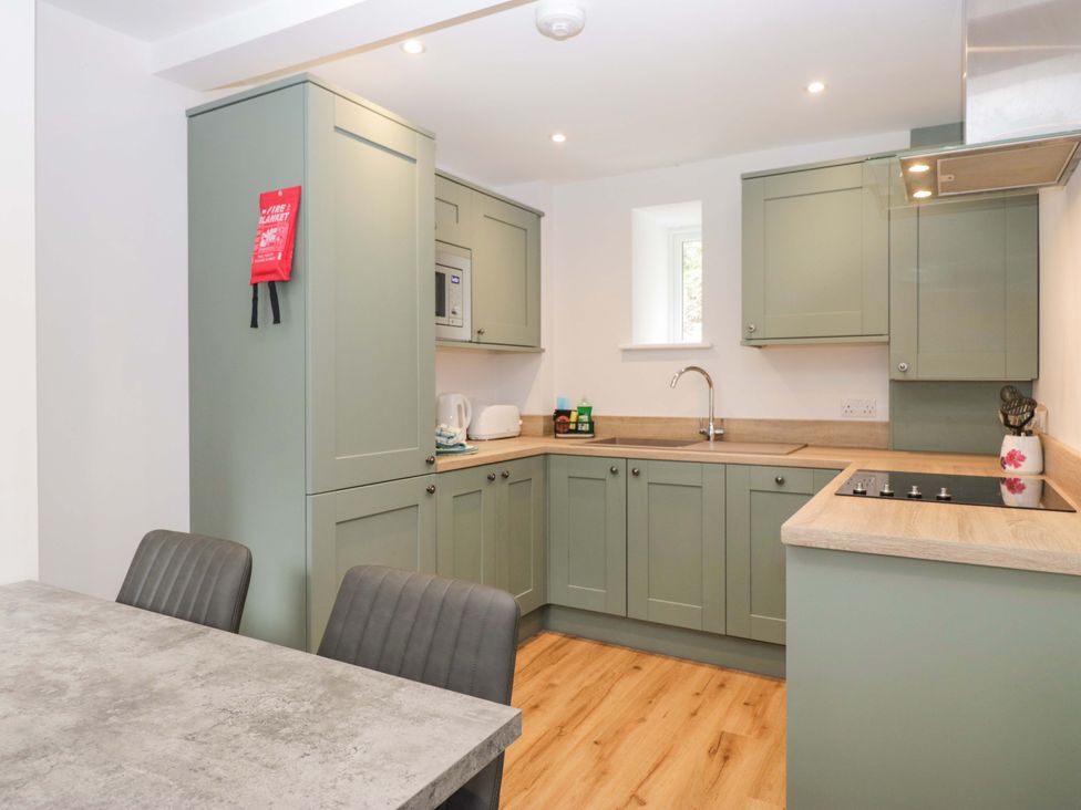 A kitchen with green cabinets and a sink at Riverside Cottage No 5 in Keswick
