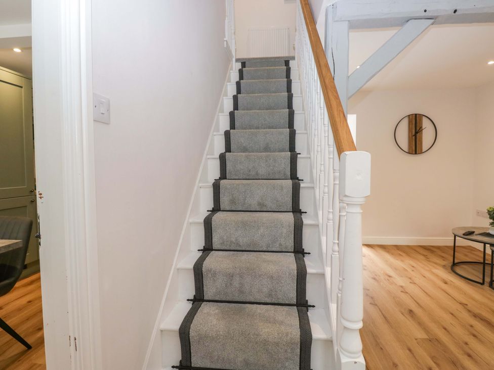 A staircase with a handrail and carpet leading to an upper level at Riverside Cottage No 5 in Keswick