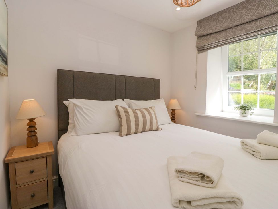 A bedroom with a bed and bedside table at Riverside Cottage No 5 in Keswick