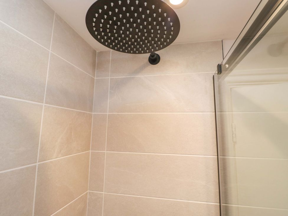 A shower head and tiles in a bathroom at Riverside Cottage No 5 in Keswick