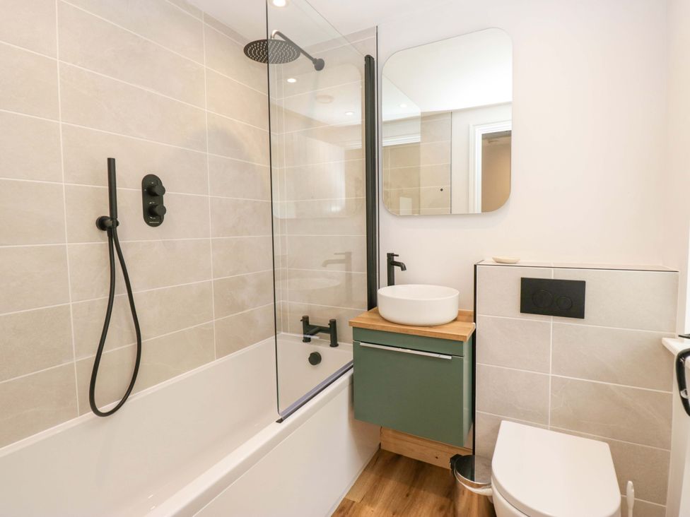 A bathroom with bathtub, shower, sink, and toilet at Riverside Cottage No 5 in Keswick