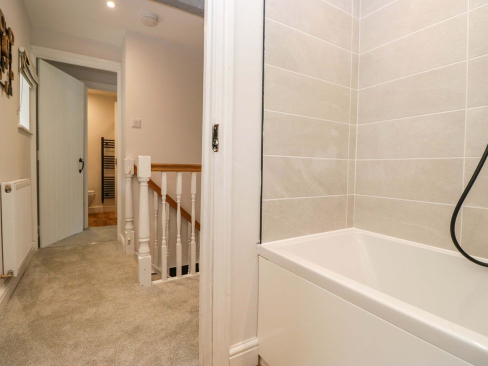 A bathroom with a bathtub and view of the staircase at Riverside Cottage No 5 Keswick