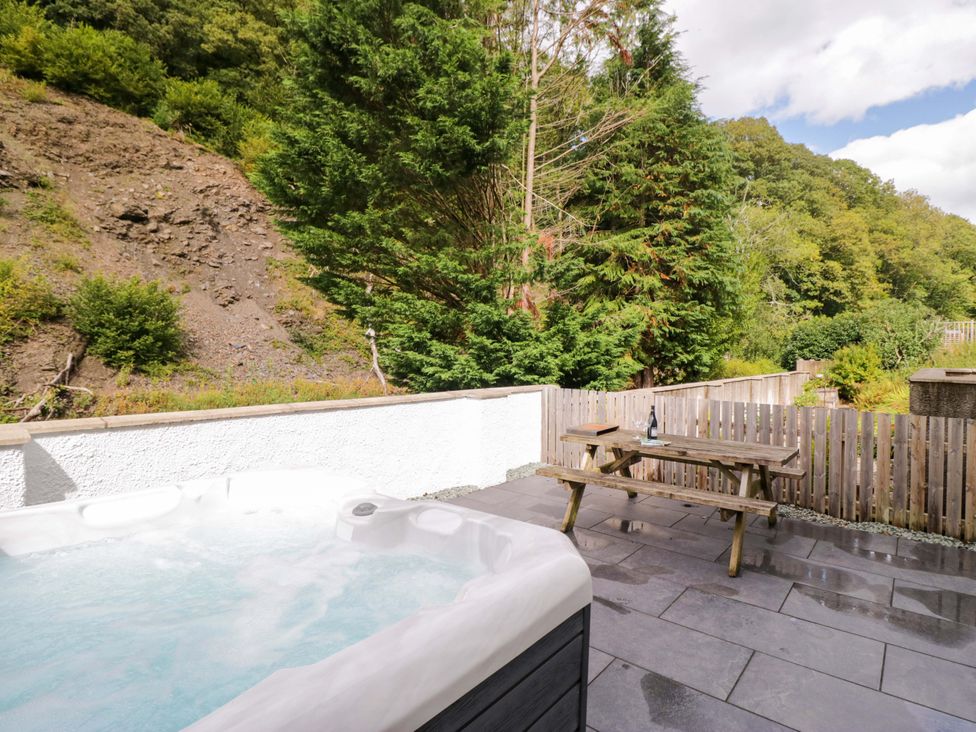 An outdoor area with a hot tub and picnic bench at Riverside Cottage No 5 in Keswick