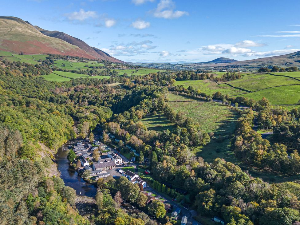 A landscape view with houses along a river and hills in the background at Riverside Cottage No 5 Keswick