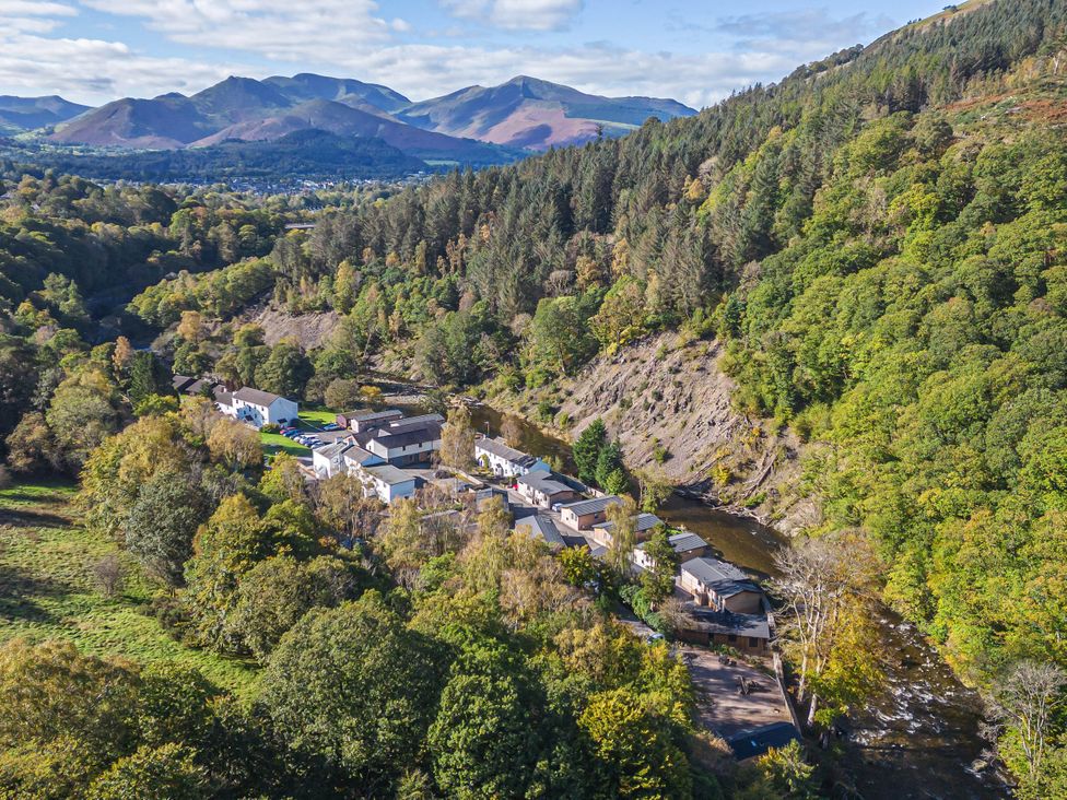 An aerial view of a village by a river surrounded by hills at Garden Cottage No 1 in Keswick