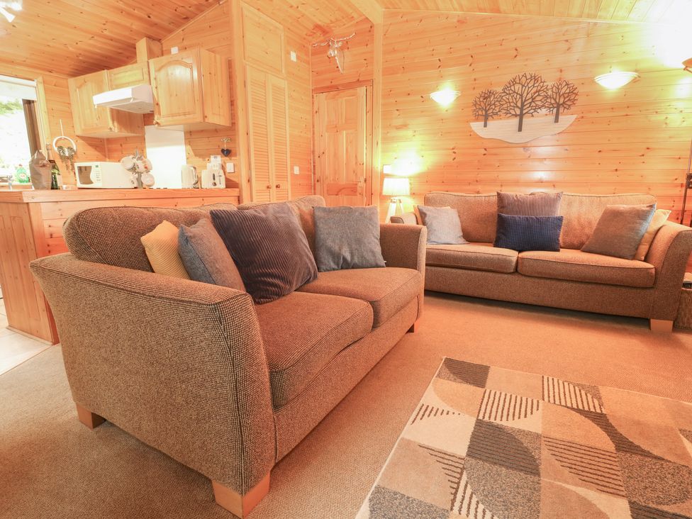 A living room with sofas and kitchenette at Derwent Lodge in Keswick