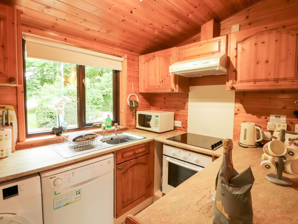 A kitchen with wooden cabinets and appliances at Derwent Lodge in Keswick