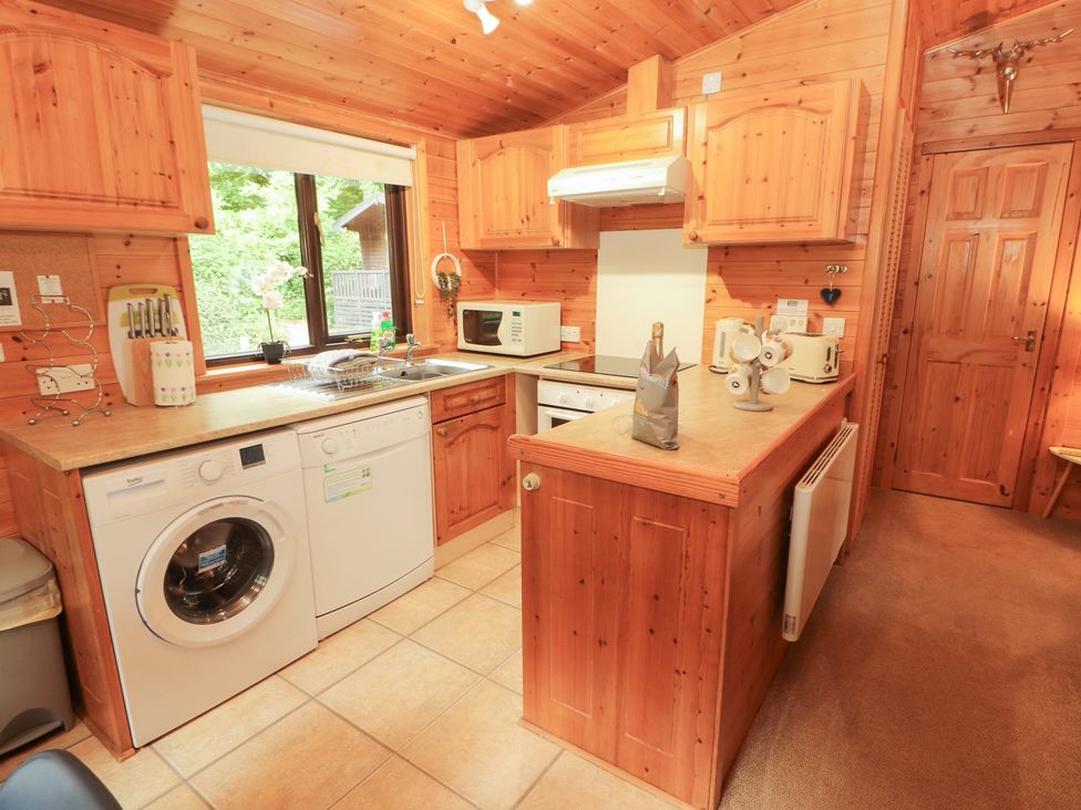 A kitchen with wooden cabinets and appliances at Derwent Lodge in Keswick