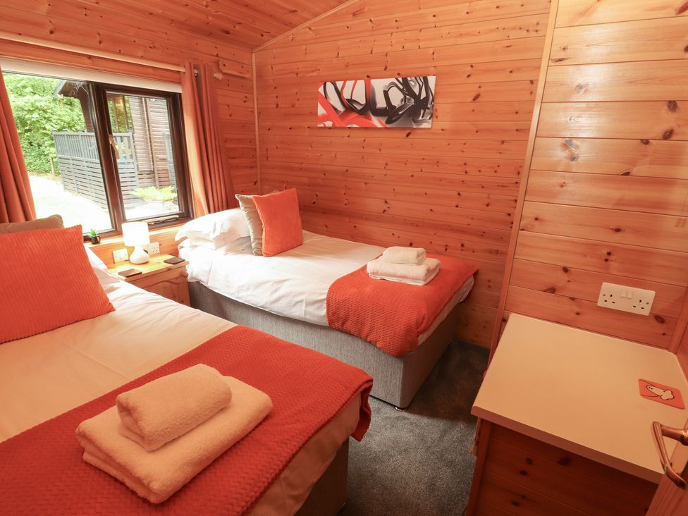 A bedroom with two beds and wooden features at Derwent Lodge in Keswick