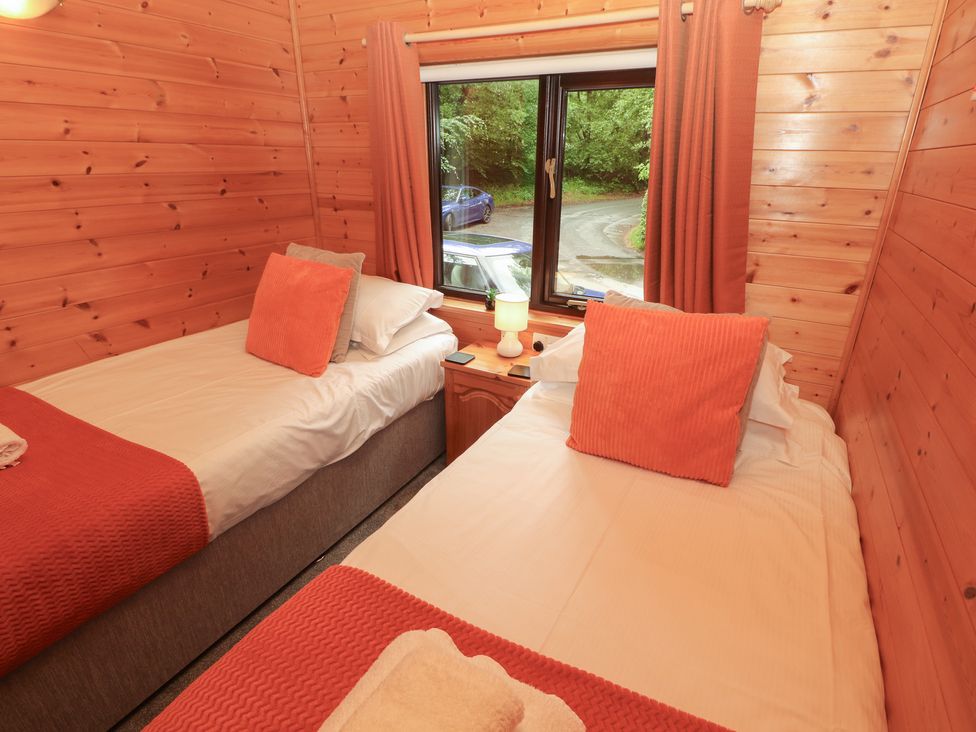A bedroom with twin beds and a lamp at Derwent Lodge in Keswick