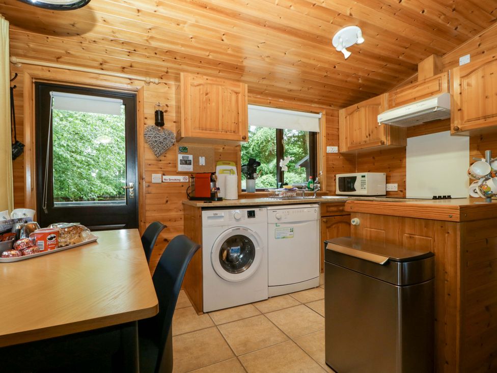 A kitchen with a washing machine and microwave at Derwent Lodge in Keswick