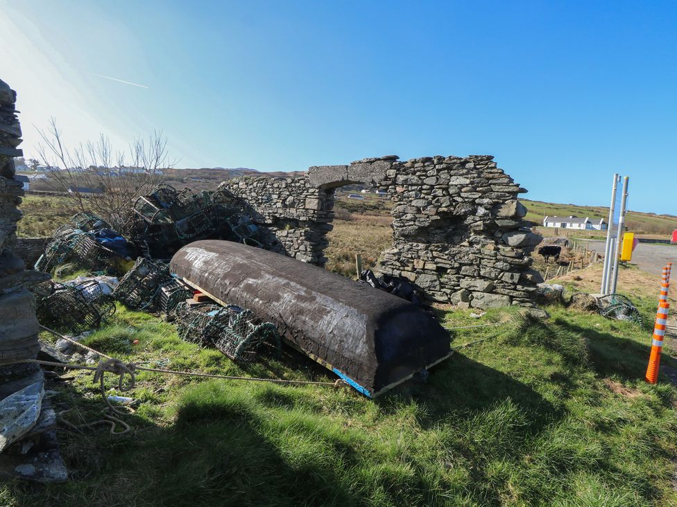 A boat and lobster traps near a stone wall outdoors at Sea View House in Tully, County Galway