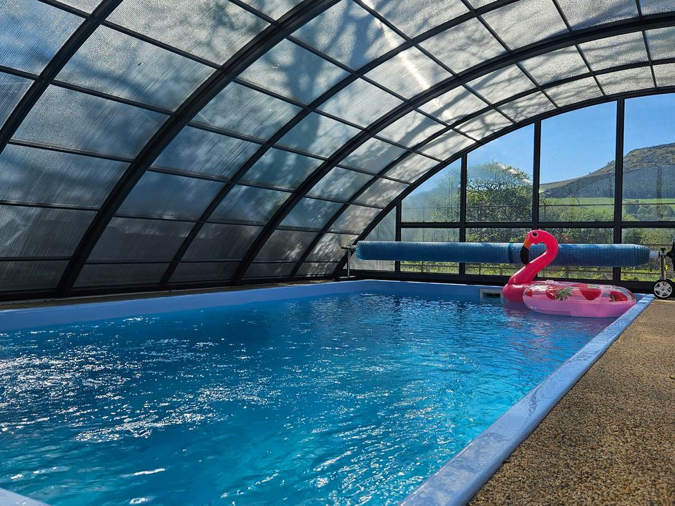 An indoor pool with a flamingo inflatable at The Keepers Lodge in Boduan near Nefyn