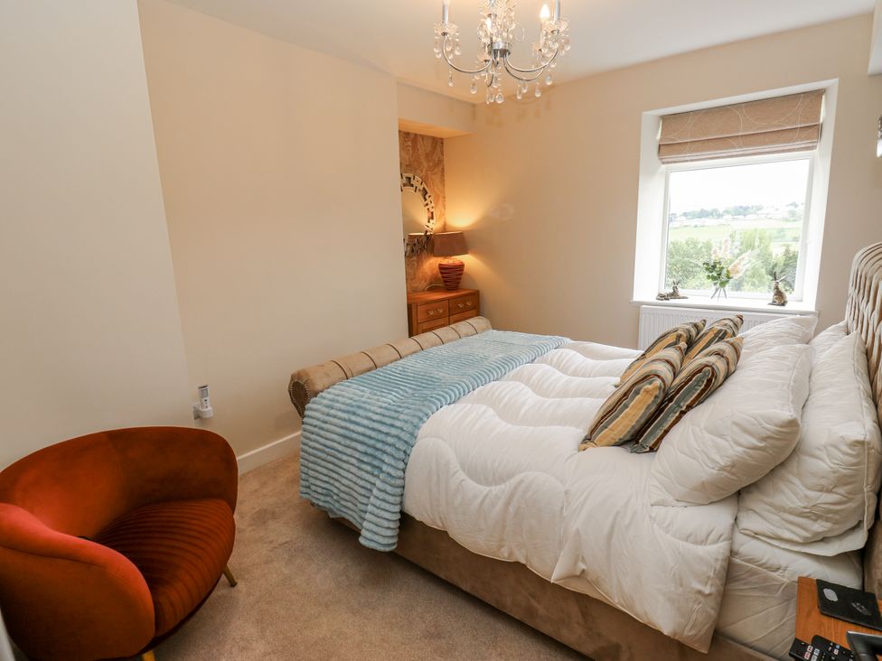 A bedroom with a bed, chair, and window at Millside View