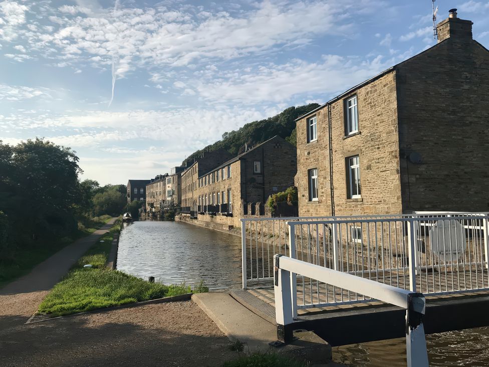 A canal with buildings alongside and a bridge at Millside View in Kildwick