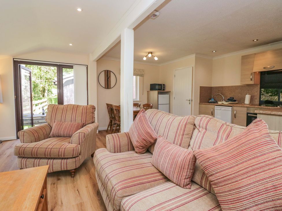 A living room with a sofa and dining area at Chestnut Timber Lodge in Keswick