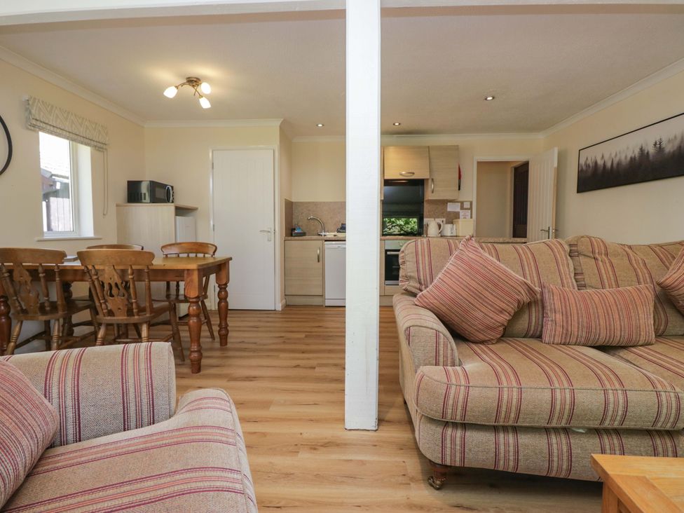 A living room with a dining area and kitchen appliances at Chestnut Timber Lodge in Keswick