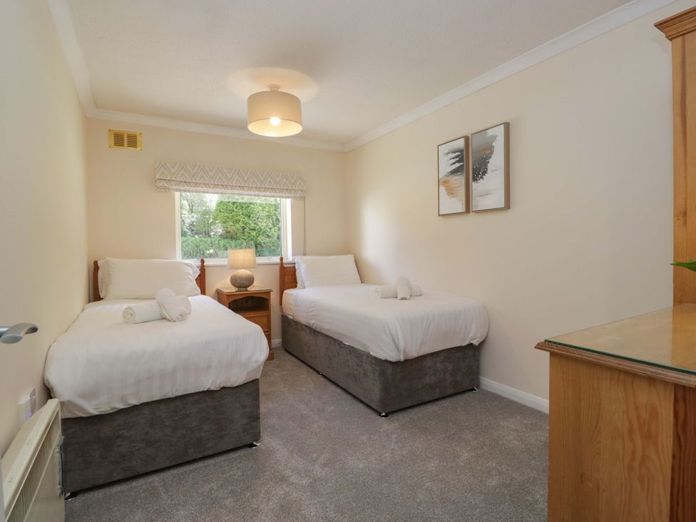 A bedroom with two beds and a lamp at Chestnut Timber Lodge in Keswick