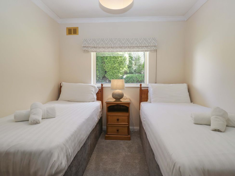 A bedroom with two single beds and a nightstand at Chestnut Timber Lodge in Keswick