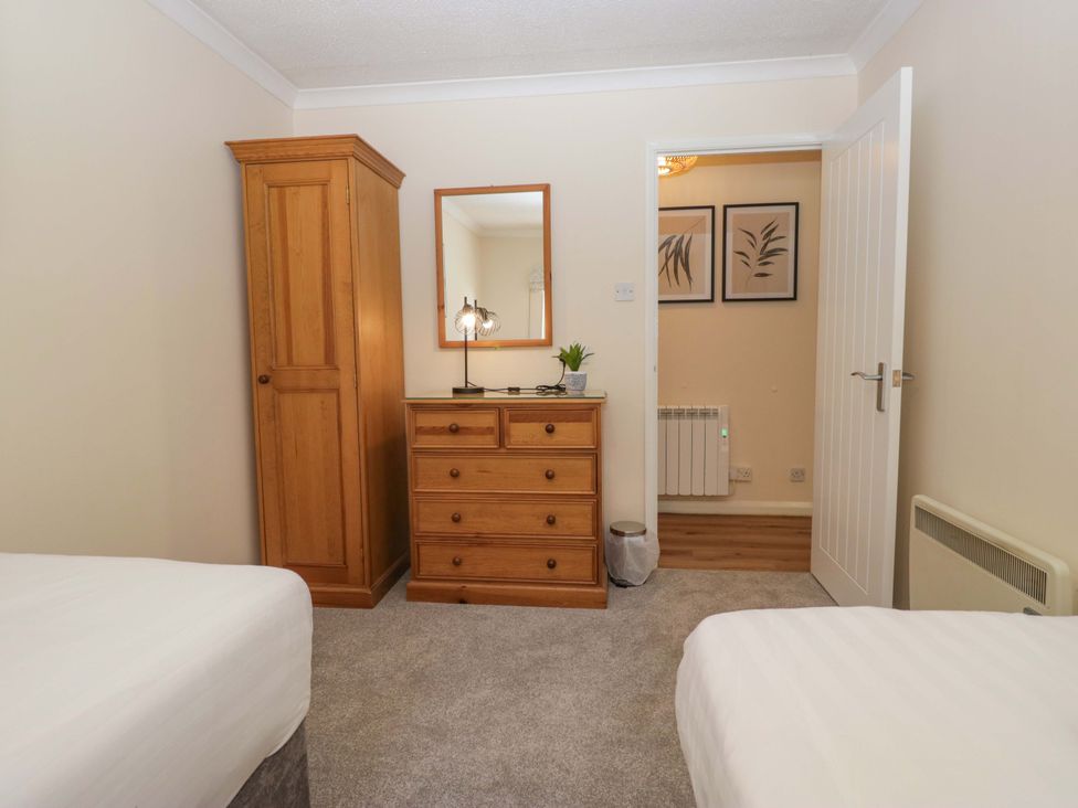 A bedroom with a bed, wardrobe, and chest of drawers at Chestnut Timber Lodge, Keswick