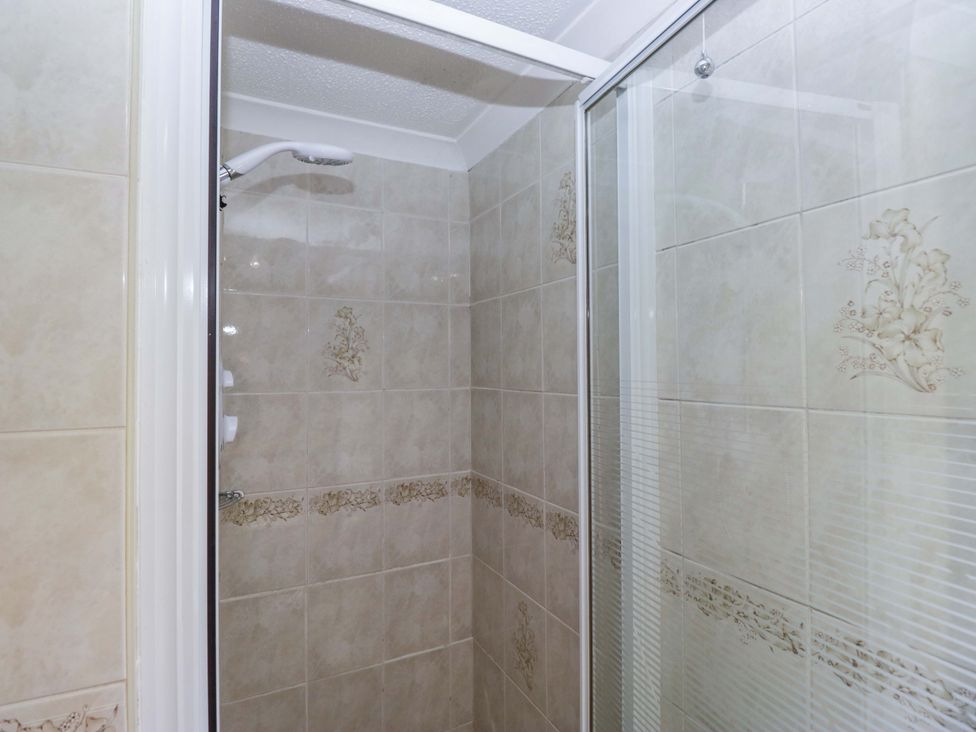 A shower area with tiles and glass door at Chestnut Timber Lodge in Keswick