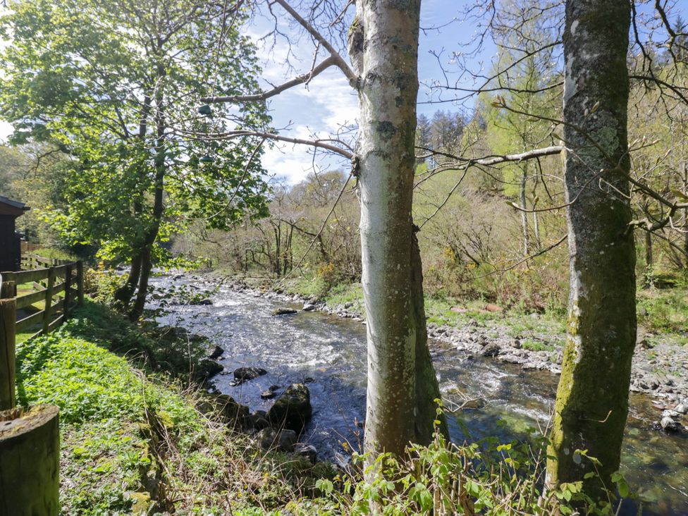 A river with trees and a wooden fence at Dogwood Timber Lodge in Keswick
