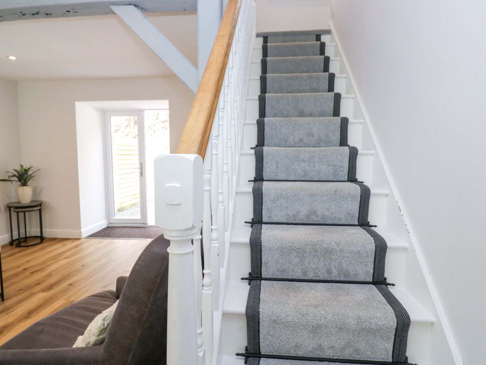 A staircase with a handrail leading to a door at Riverside Cottage No 4 in Keswick
