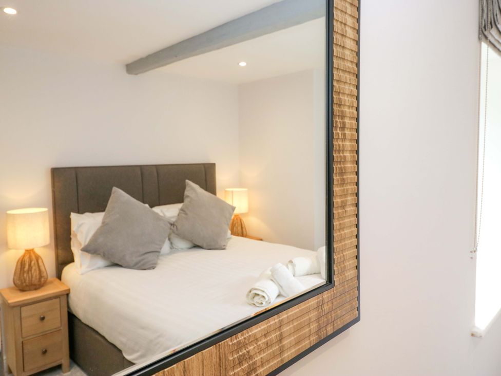 A bedroom with a bed, nightstands, lamps, and towels at Riverside Cottage No 4 in Keswick
