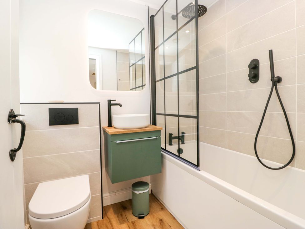 A bathroom with a shower, bathtub, sink and toilet at Riverside Cottage No 4, Keswick