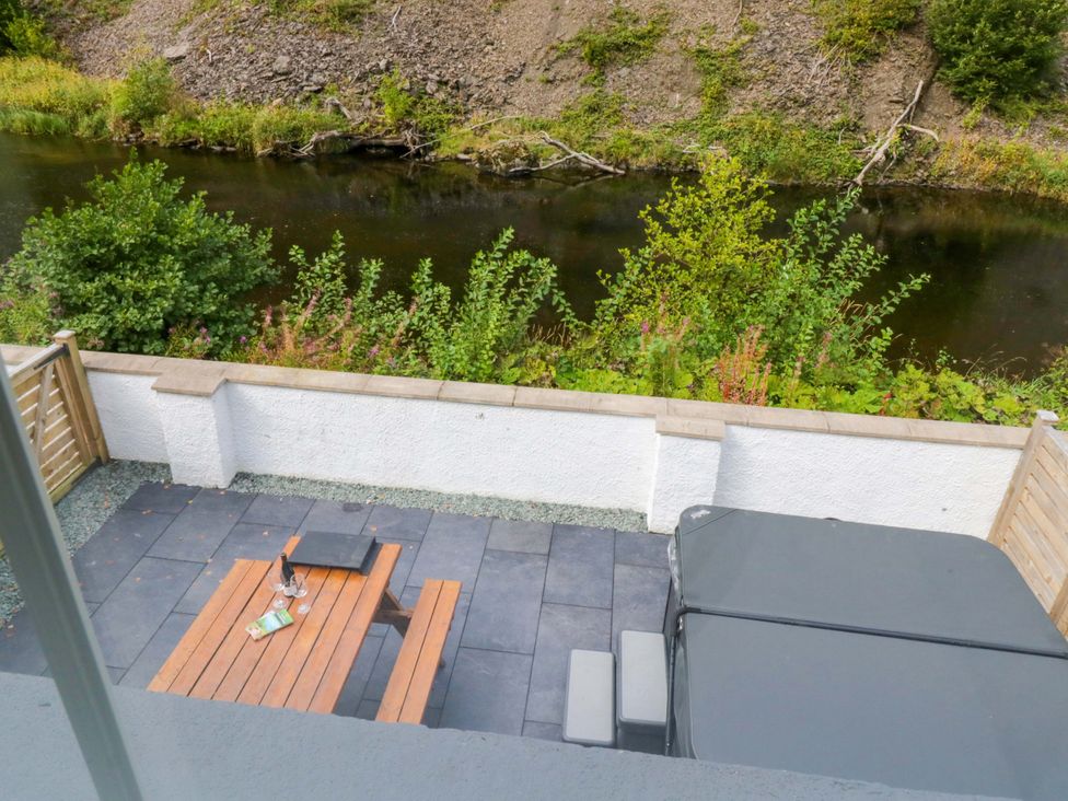 An outdoor area with a patio table and hot tub at Riverside Cottage No 4 in Keswick