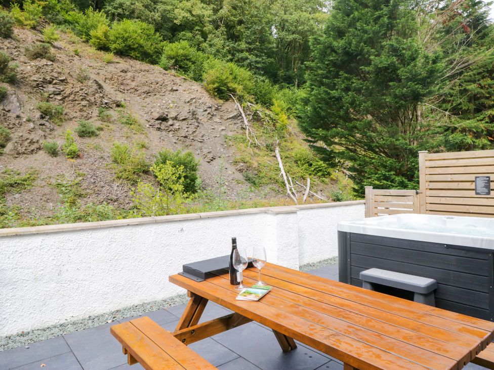An outdoor area with a table and hot tub at Riverside Cottage No 4 in Keswick