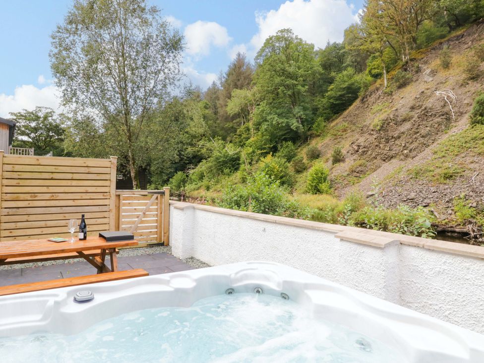 A hot tub and table with drinks in an outdoor area at Riverside Cottage No 4 Keswick