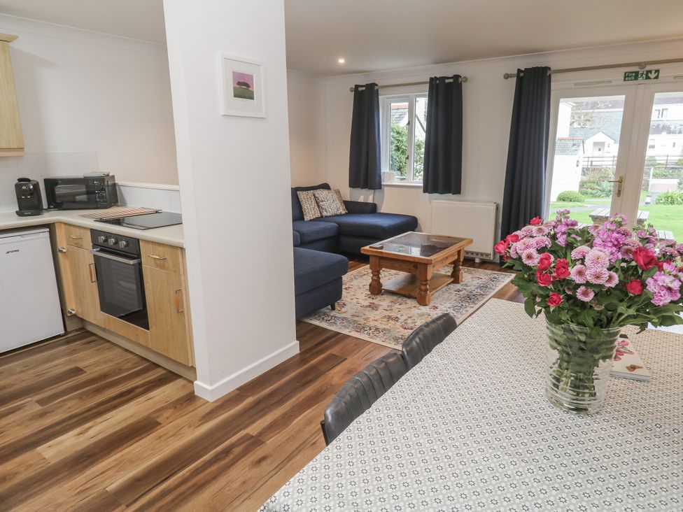 An open-plan living area with a sofa and dining table at Chellowdene Cottage in Falmouth