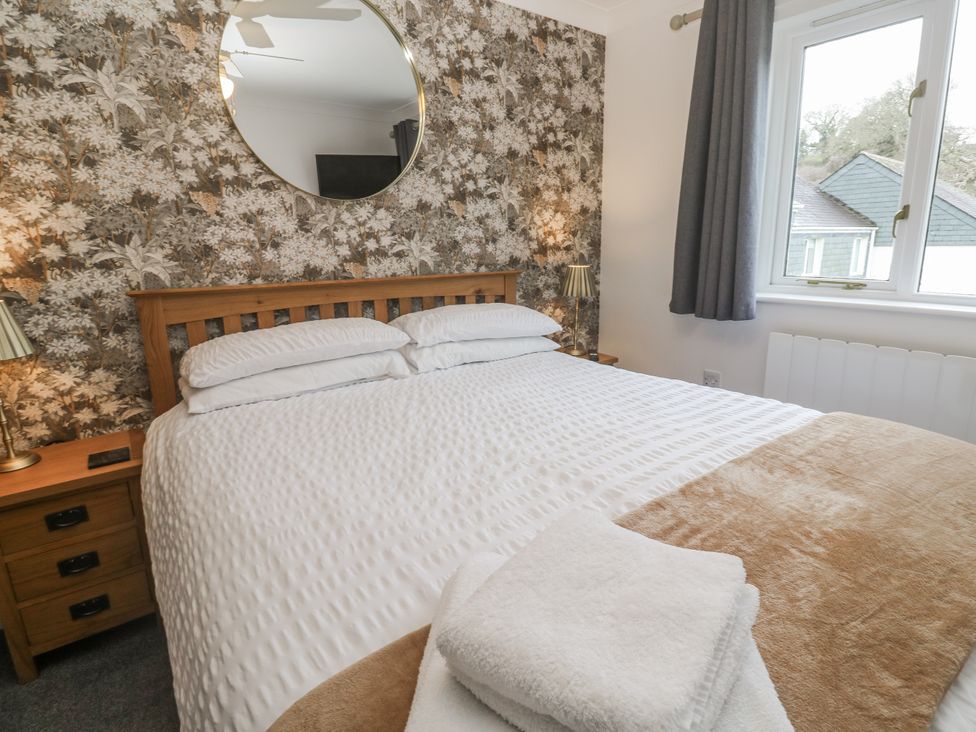 A bedroom with a bed and nightstand at Chellowdene Cottage in Falmouth