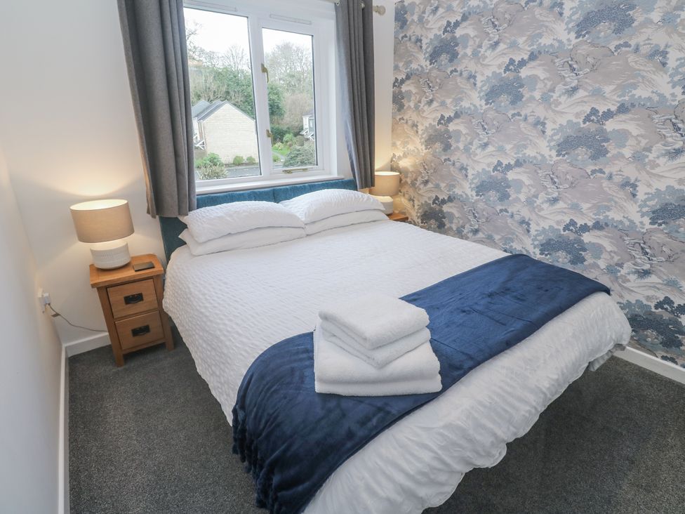 A bedroom with a bed and bedside table at Chellowdene Cottage in Falmouth