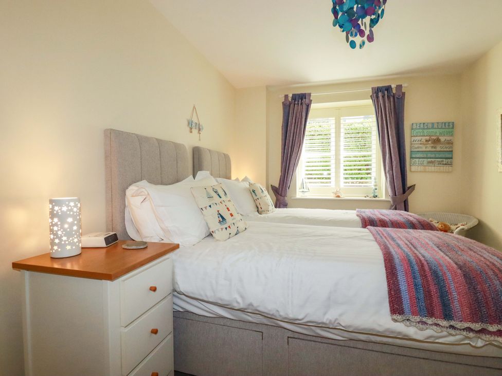 A bedroom with two beds and a bedside table at Pen-Y-Les in Wadebridge