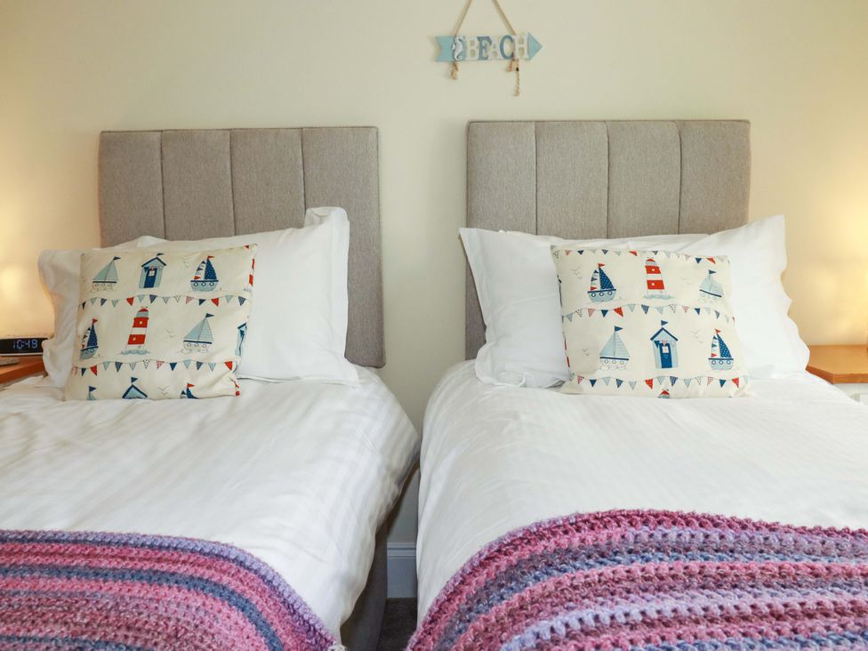 A bedroom with two beds and decorative pillows at Pen-Y-Les in Wadebridge