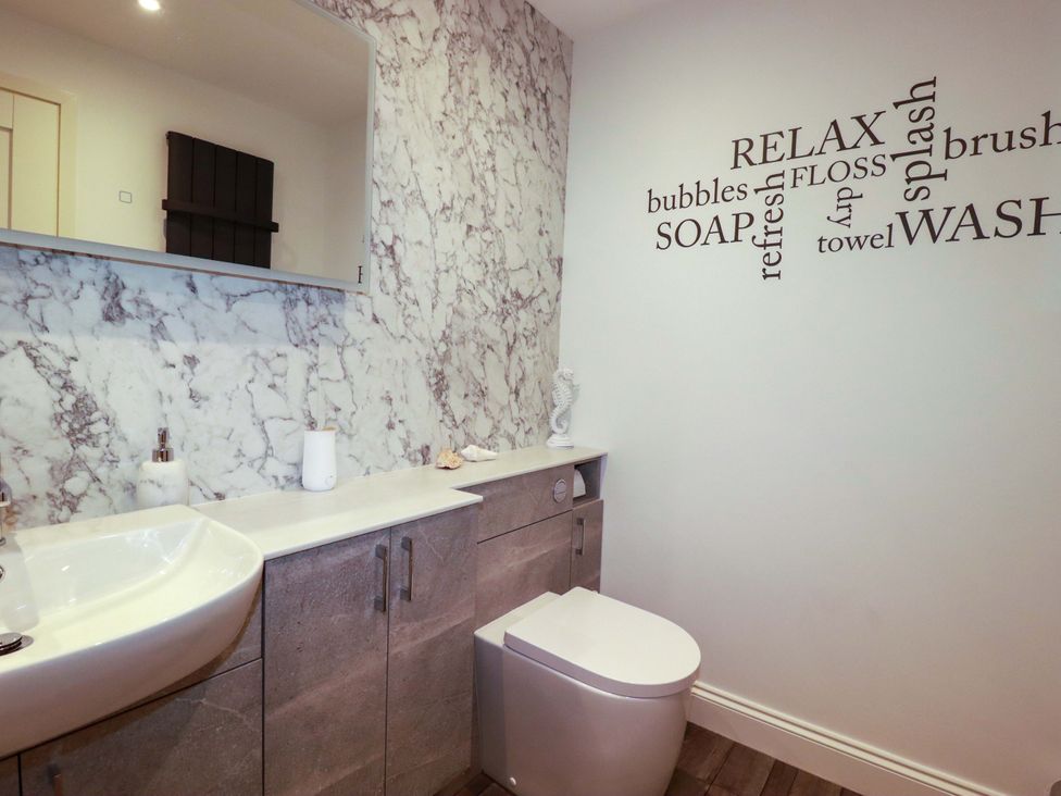 A bathroom with a sink, toilet, and mirror at Pen-Y-Les Wadebridge