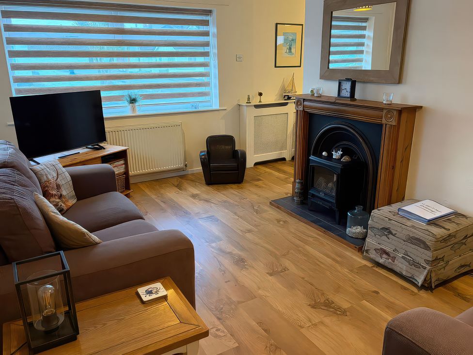 A living room with a sofa and television at Jacuma in Rhosneigr