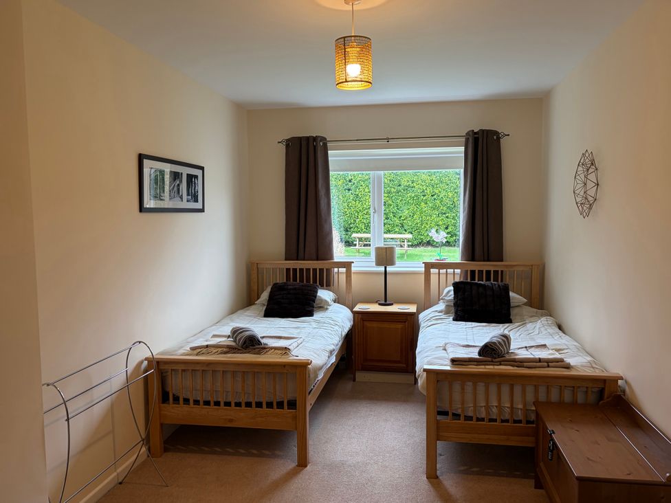 A bedroom with two beds and a window at Jacuma in Rhosneigr
