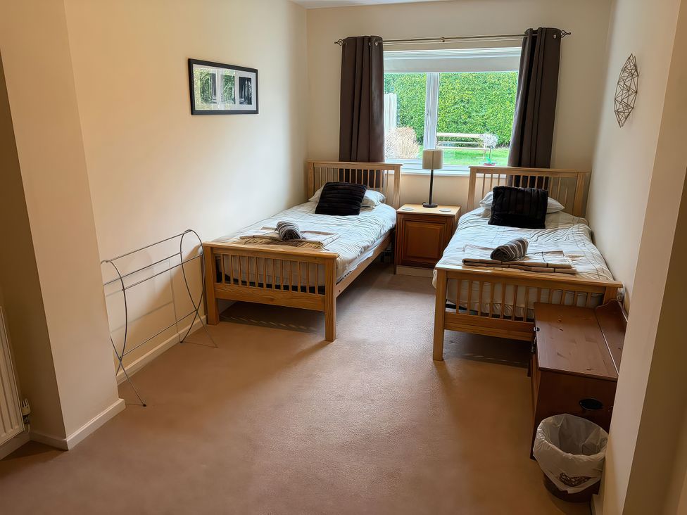 A bedroom with two beds and a nightstand at Jacuma in Rhosneigr