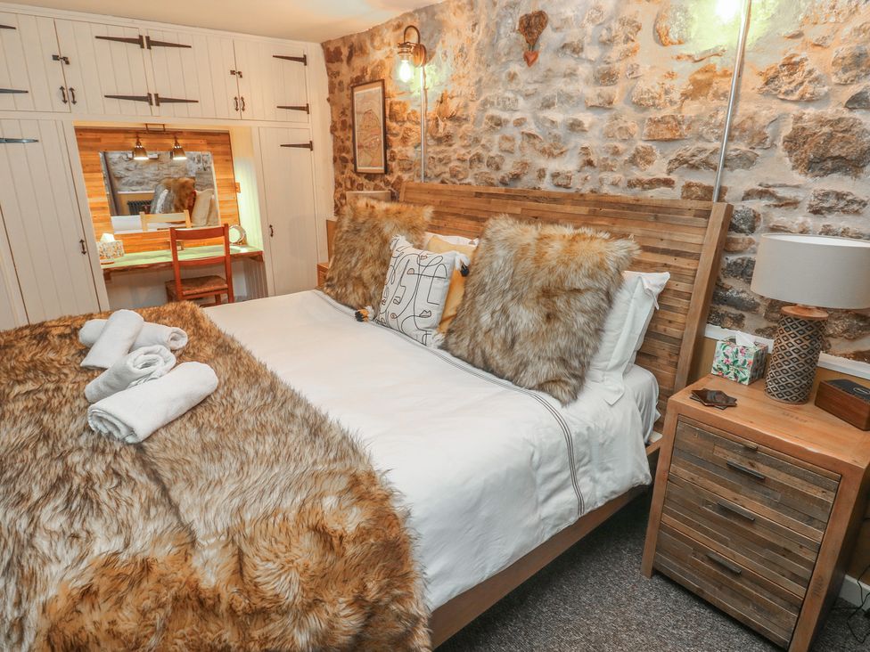 A bedroom with a bed and a wardrobe at Coach House in Haverfordwest near Broad Haven